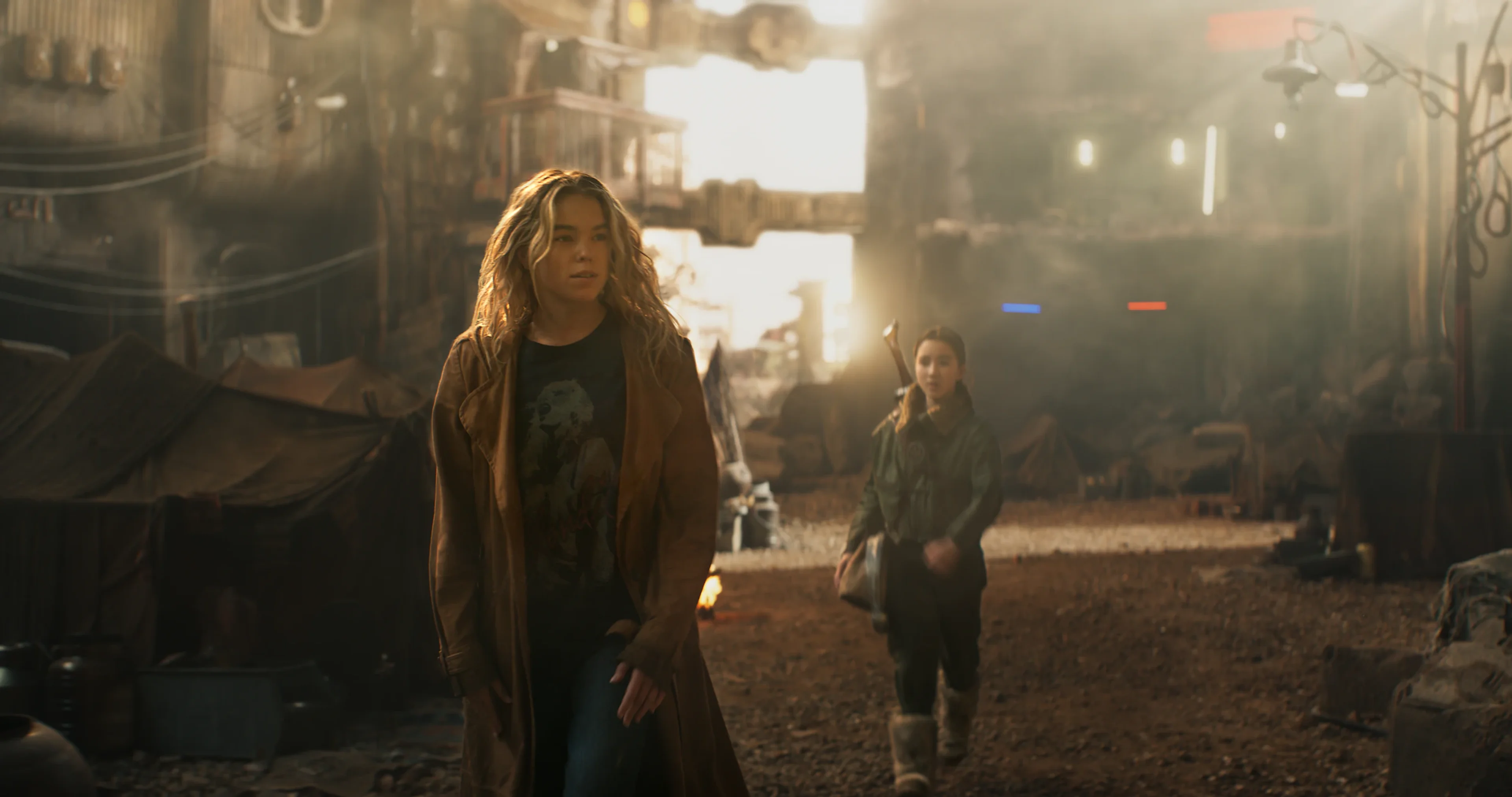 Kara walks through an alien settlement with Ruthye behind her.