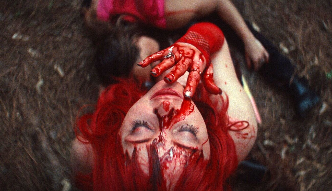 Jamie lies on the ground with stage blood on her face and hand in Marrow.