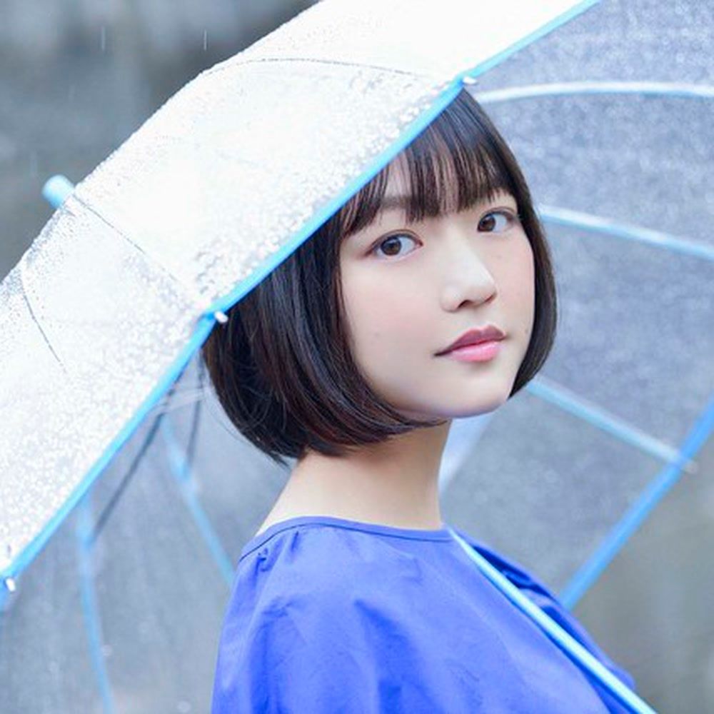 Japanese voice actor Shino Shimoji poses under a clear umbrella in an official FlyingDog portrait.