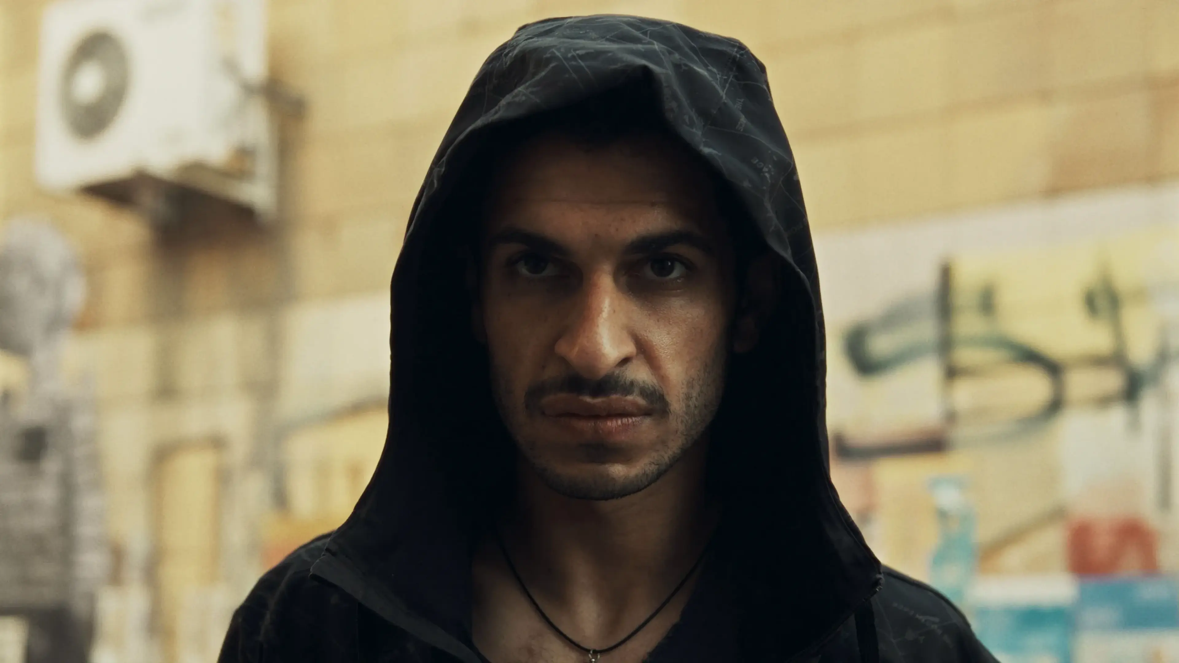 A hooded man looks forward on a Berlin street in City of Blood.