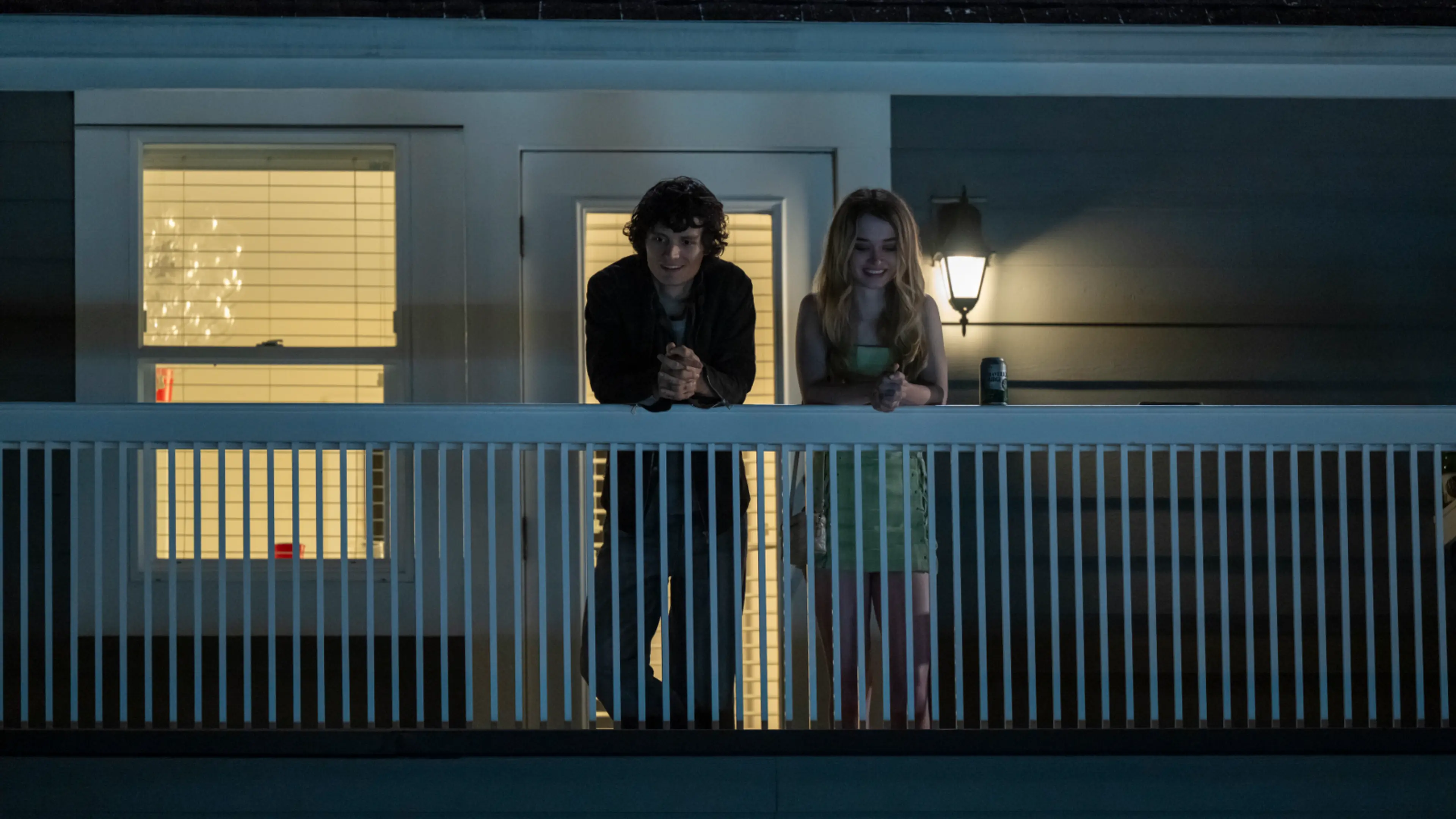 Arthur Conti as Billy Nolan and Alison Thornton as Chris Hargensen stand together on a dark balcony.