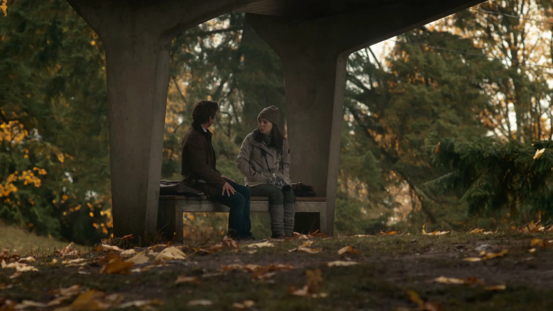 Jeremy Allen White as Jeff Horwitz speaks with Mikey Madison as Frances Haugen at an outdoor bench.