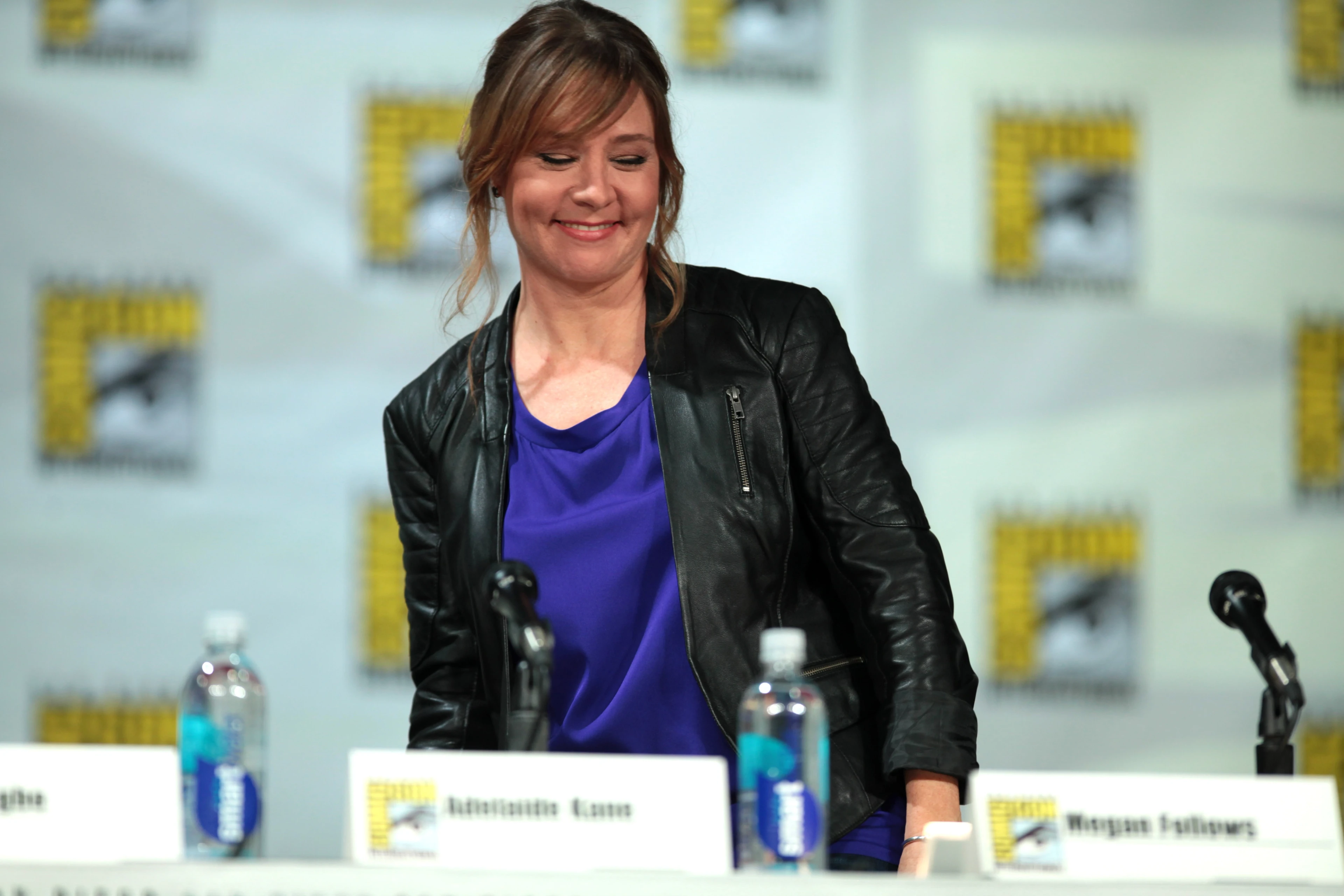 Megan Follows at a Comic-Con panel, wearing a black jacket over a purple top.