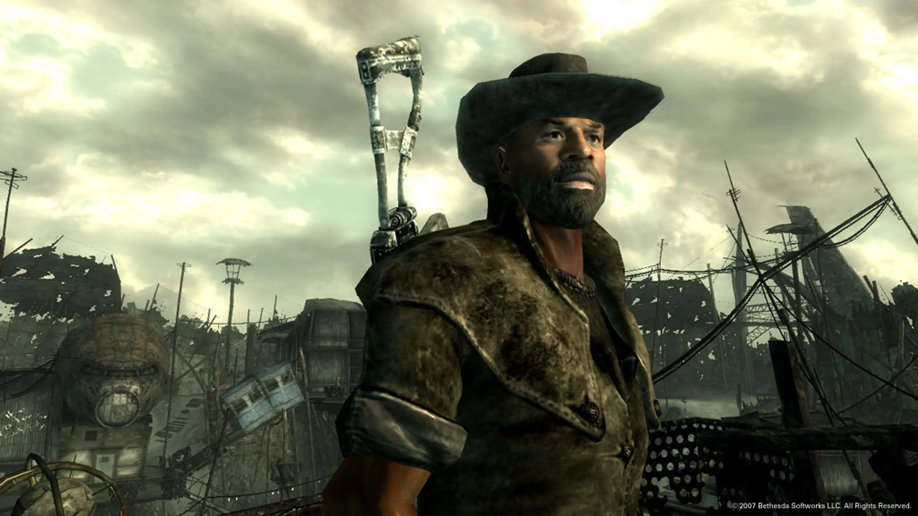 A bearded wasteland survivor in a wide-brimmed hat stands among ruined structures in Fallout 3.