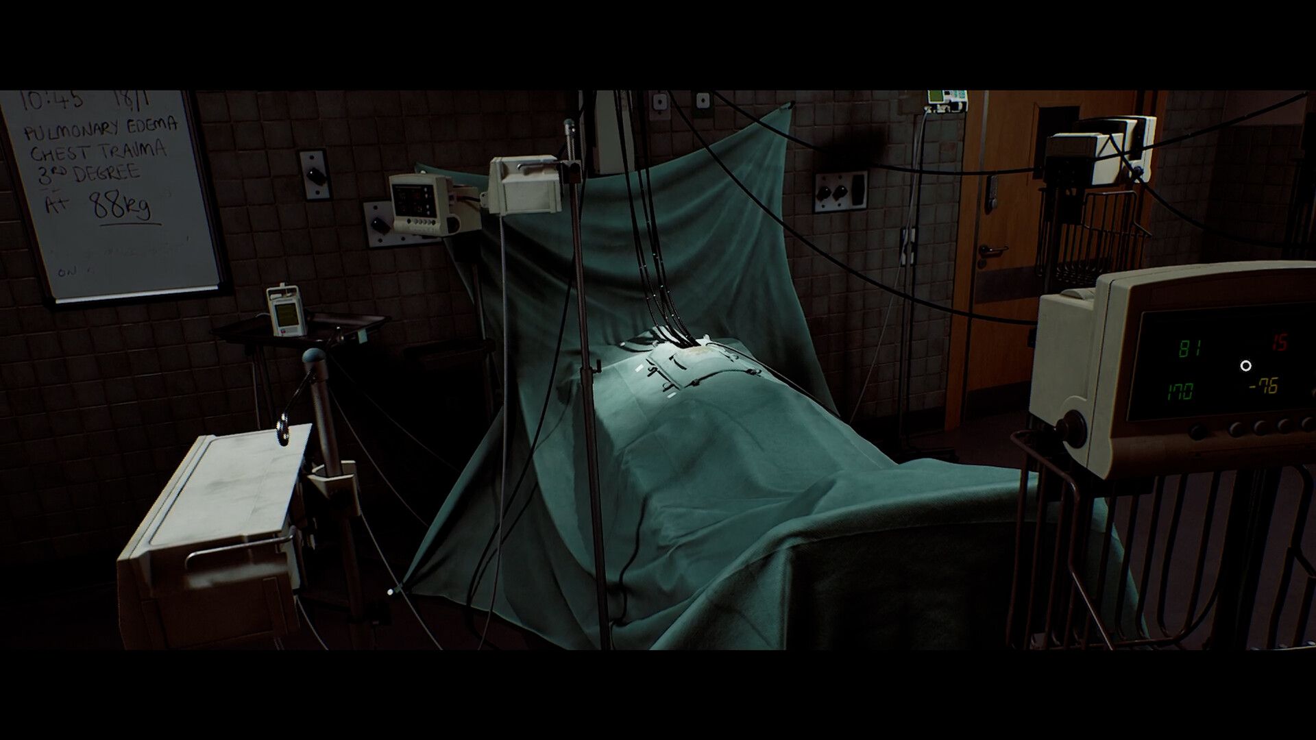 A clinical bed with a green covering sits beside wires and medical monitoring equipment.