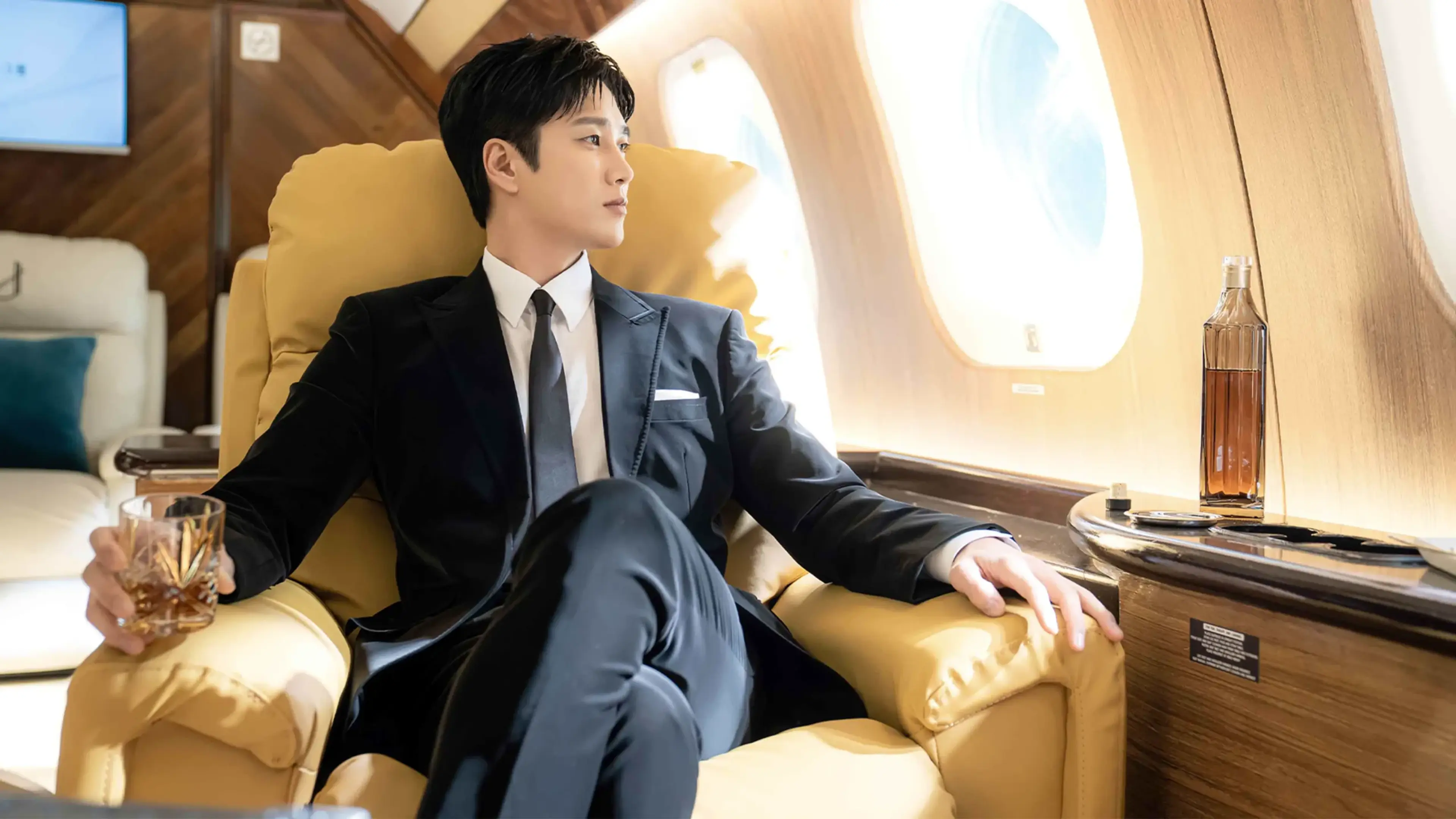 Jin I-soo sits beside the window of a private jet.