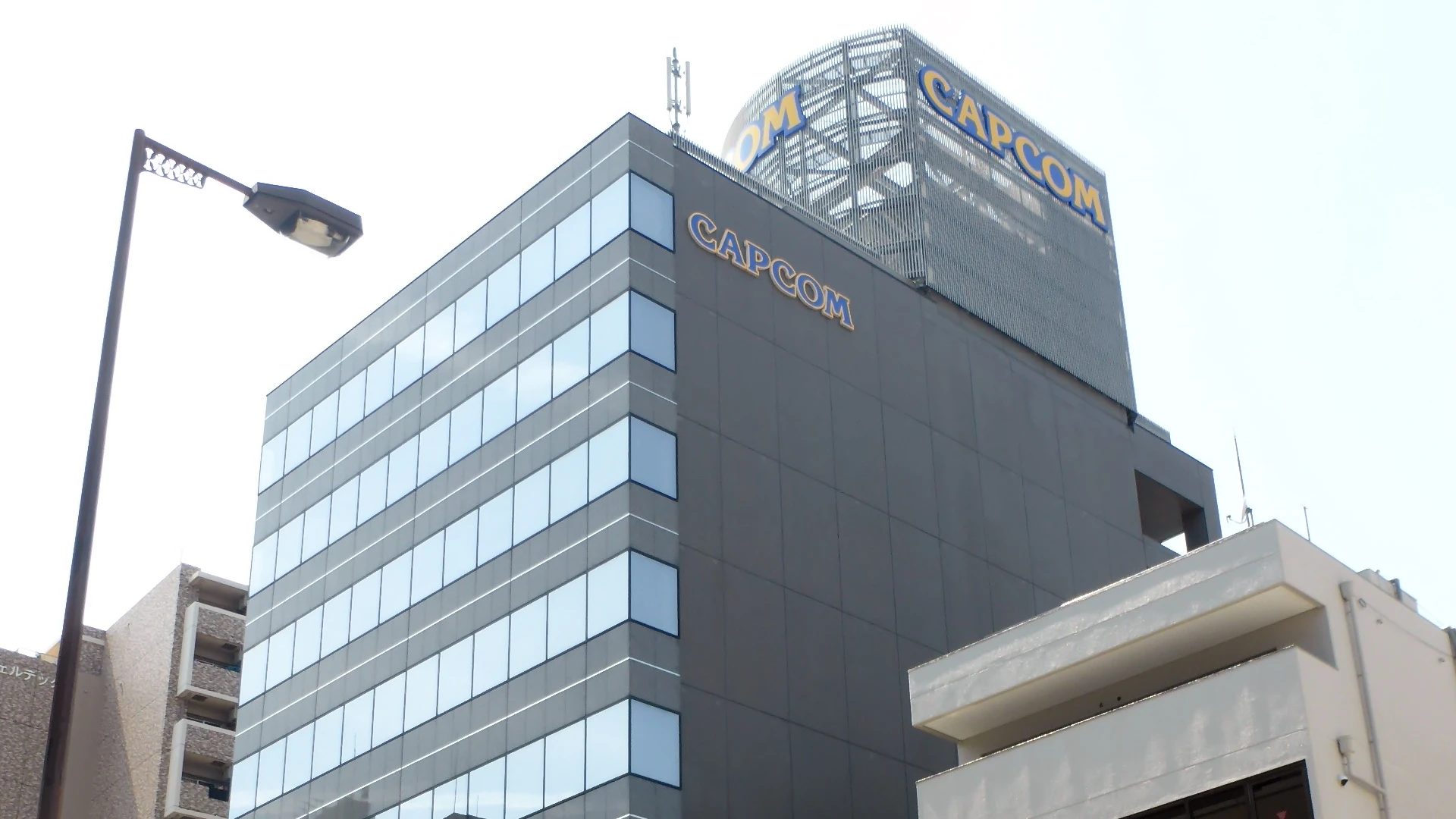 Capcom’s Osaka headquarters, with blue-and-yellow CAPCOM signs above its glass facade.