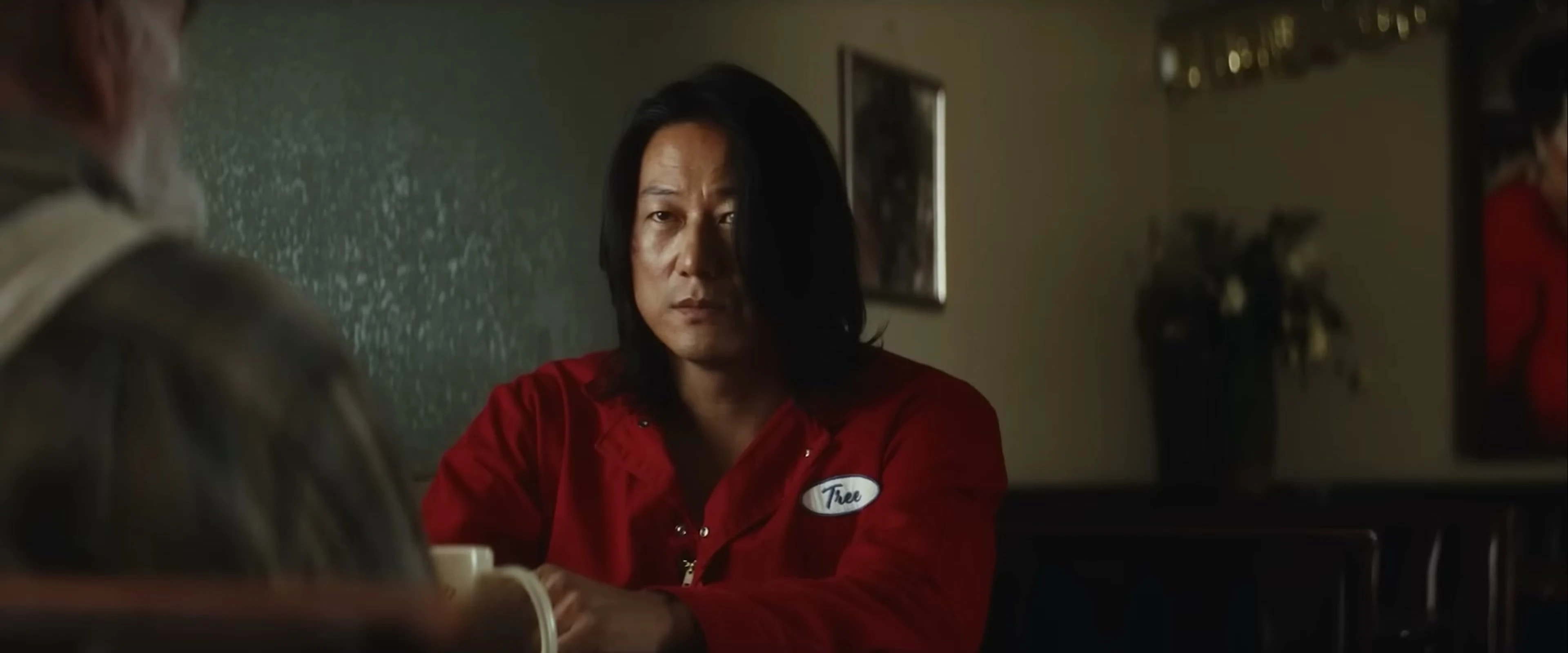 Sung Kang as Tree sits in a red work uniform in the film Drifter.