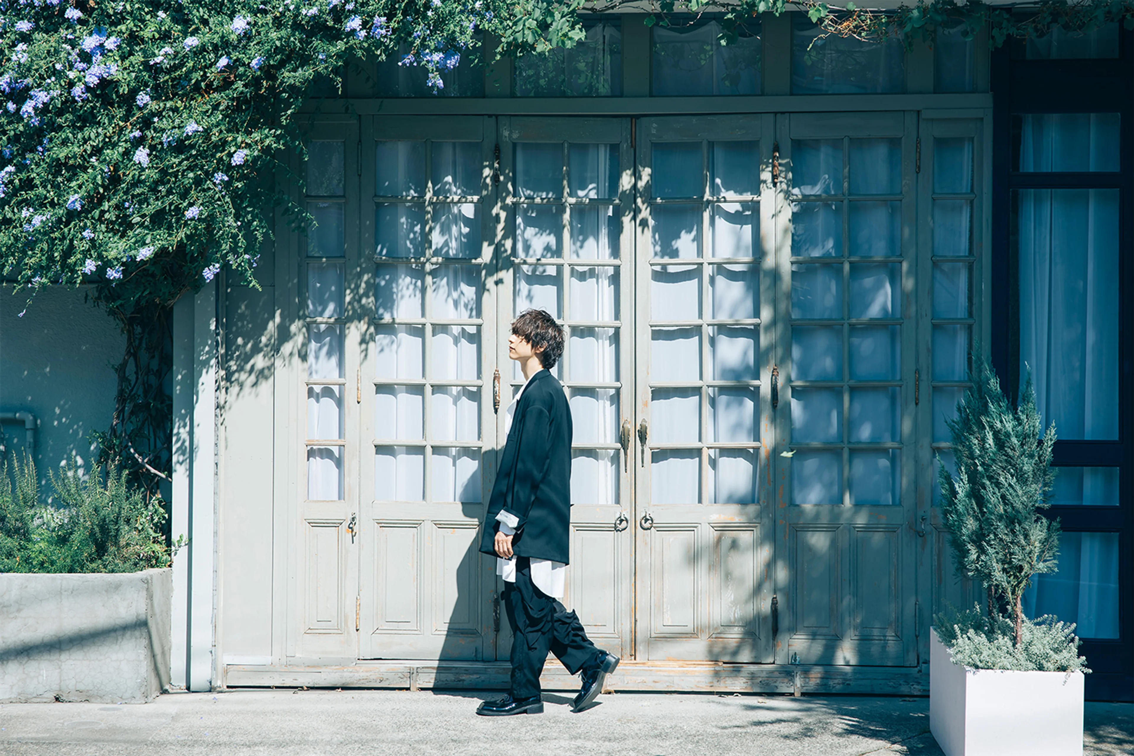 A character walks past a flower-covered doorway in bright official My Happy Marriage promotional artwork.