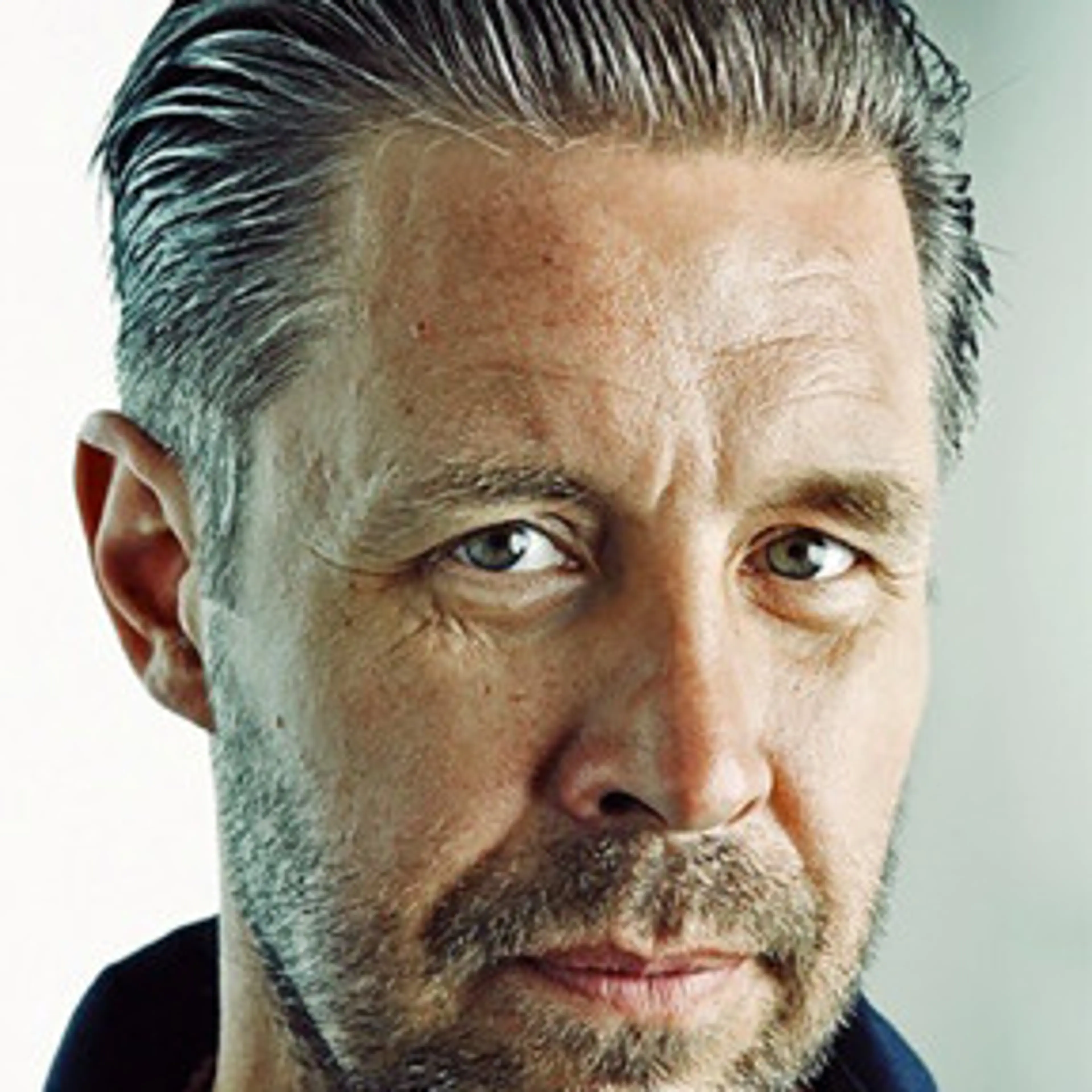 Portrait of Paddy Considine with slicked-back hair and a short beard.